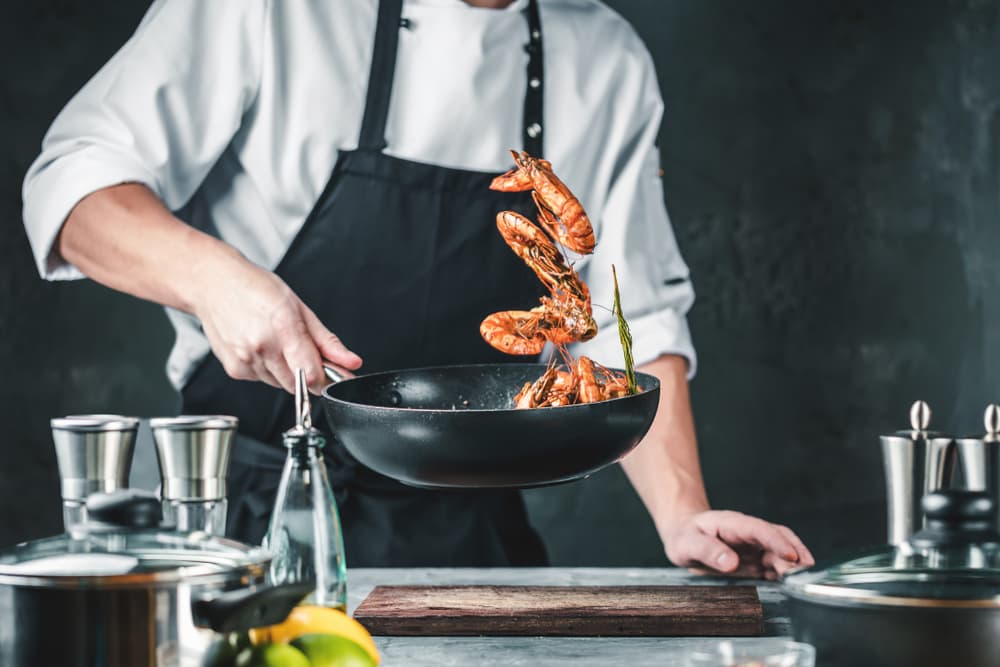 Chef flipping prawns in a pan